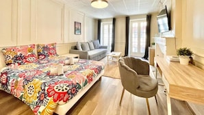 A hotel room with a bed, a sofa, a chair, a desk, a TV, and a window. - Historic Centre Studio, 50 m from Quimper Cathedral, Charm & Comfort (Quimper)