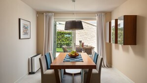 A dining area with a wooden table, chairs, a fruit bowl, and a view of a garden through a glass door. - Villa Ginevra by Villas Guide (Tar)