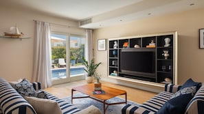 A living room with a pool view, a TV, and a bookshelf.