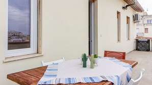 Ein Essbereich mit einem Tisch für zwei Personen, einer hölzernen Bank und Blick auf die Stadt durch ein Fenster.
