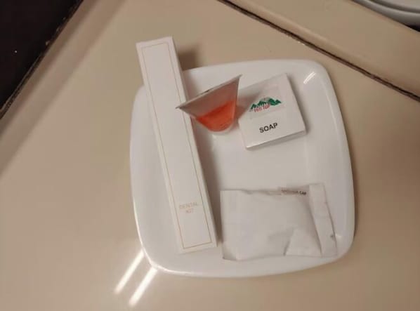 Una bandeja blanca con una pastilla de jabón, una toalla doblada y una caja sobre una encimera.