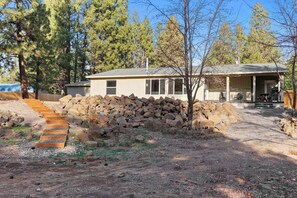 A single-story house with a stone wall and a wooden staircase leading to the front door. - Just Around the Bend For 8 (Bend)