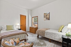 A bedroom with two beds, a wooden wardrobe, a small table with a lamp, and a window with a view of trees. - Just Around the Bend For 8 (Bend)