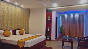 A hotel room with a bed, a small table, and a seating area. - Diamond Vaishali (Kullu)