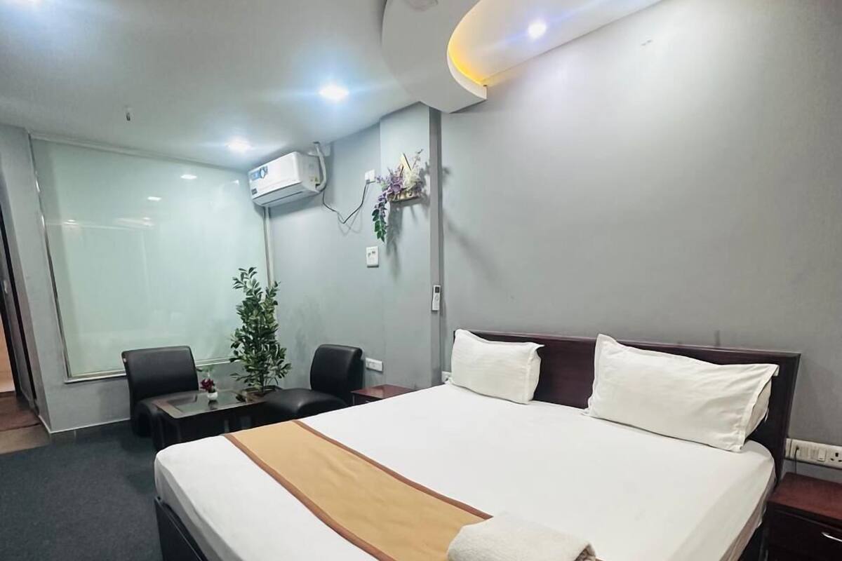 Ein modernes Hotelzimmer mit einem großen Bett, einem Schreibtisch, einem Stuhl und einer Zimmerpflanze.