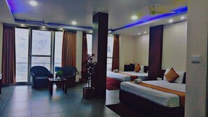 A hotel room with a large window, a sofa, a chair, and two beds. - Diamond Vaishali (Kullu)
