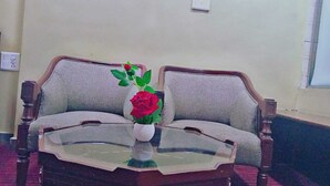 A room with a sofa and a glass-top coffee table. - Diamond Vaishali (Kullu)