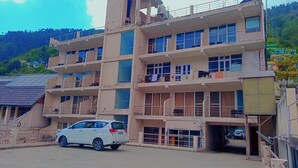 A multi-story building with balconies and a car parked in front. - Diamond Vaishali (Kullu)