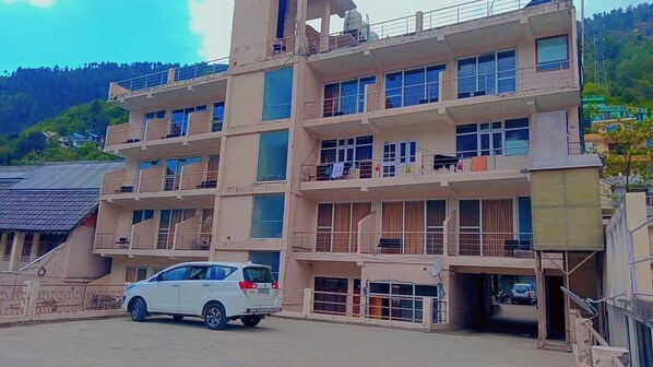 A multi-story building with balconies and a car parked in front. - Diamond Vaishali (Kullu)