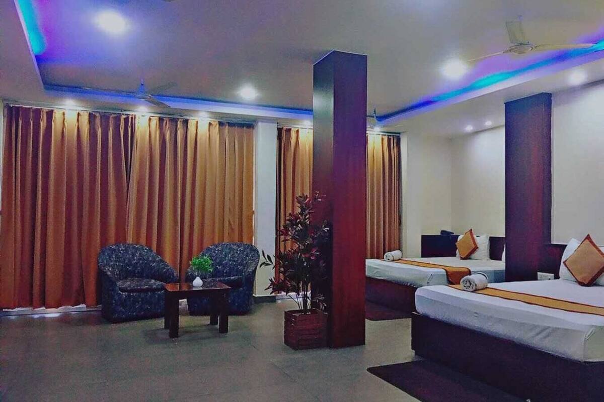 Ein Hotelzimmer mit zwei Betten, einem Schlafsofa, einem Sessel und einem kleinen Tisch.