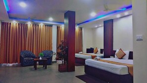 A hotel room with two beds, a sofa, a chair, and a small table. - Diamond Vaishali (Kullu)