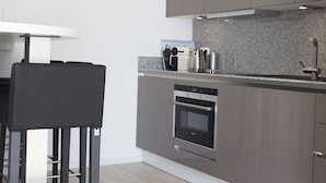 A modern kitchen with grey cabinets, a built-in oven, and a stainless steel range hood. - Refugium 2 (Emsdetten)