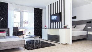 A modern bedroom with a bed, a TV, a desk, and a chair. - Refugium 2 (Emsdetten)