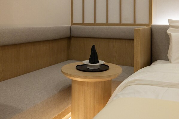 Habitación de hotel ordenada con cama, mesita de noche y panel de pared.