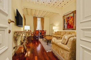 Une pièce avec un plancher en bois, un canapé, une table, des chaises, un téléviseur et un tableau.