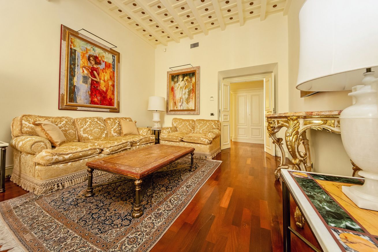 Un salon spacieux avec un grand canapé, une table basse et deux tableaux accrochés aux murs.