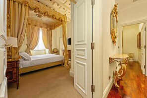 Une chambre à coucher luxueuse avec un lit à baldaquin, une table de chevet avec une lampe et un grand miroir au mur.
