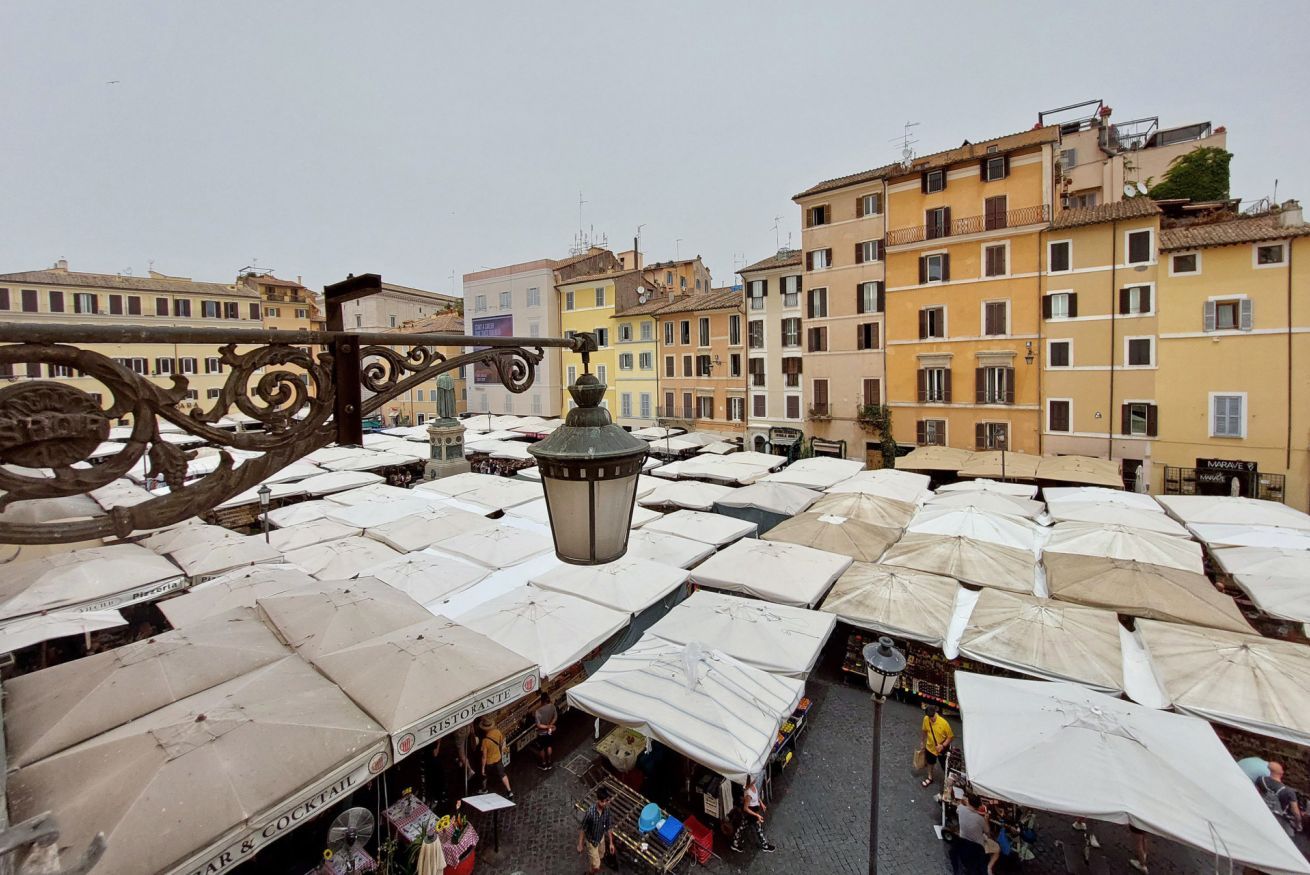 A crowded outdoor market with numerous white umbrellas and stalls.