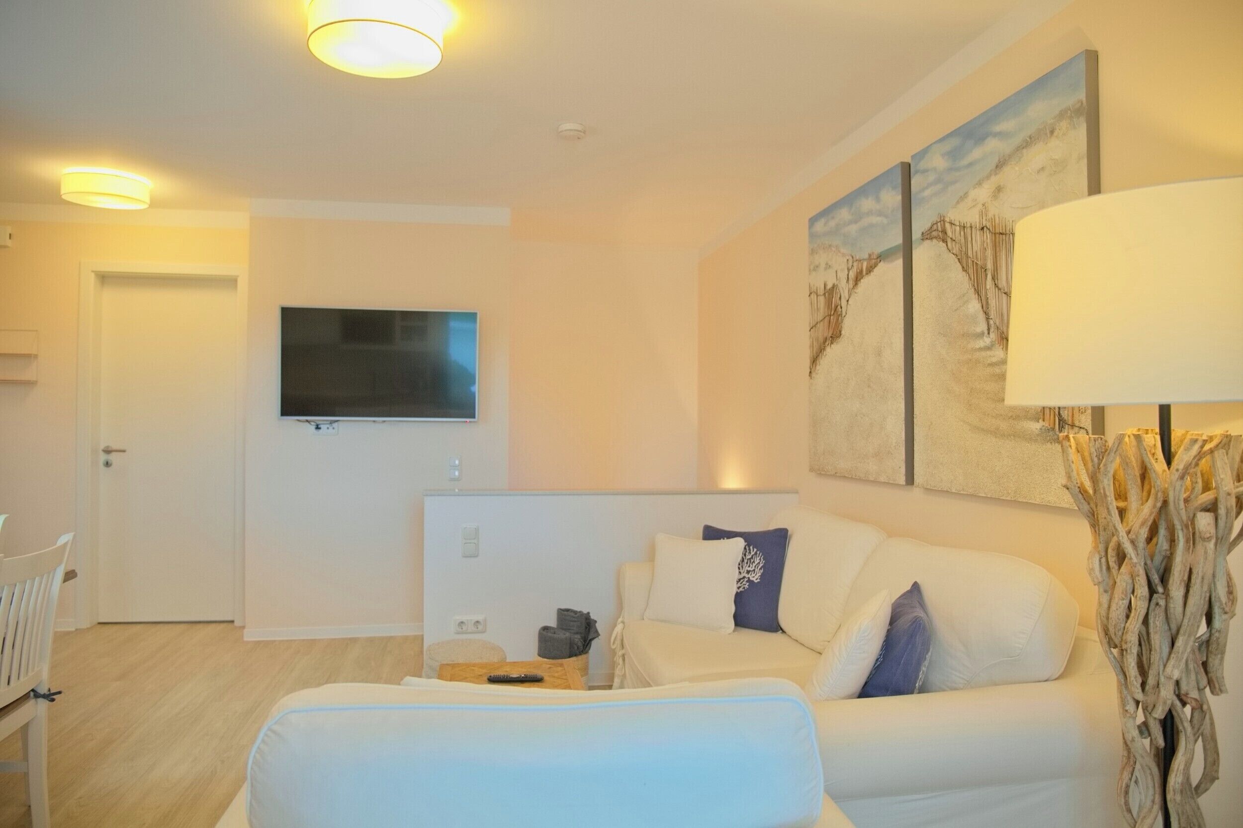 A modern living room with a sofa, a coffee table, and a TV mounted on the wall.