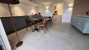 A modern kitchen with a dining area, featuring a wooden table and chairs, a kitchen island, and a staircase leading to an upper level. - Appart heights of Ollioules in magnificent house, exceptional sea view (Ollioules)