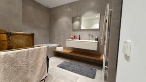 A modern bathroom with a bathtub, a vanity with a mirror, and a shower area. - Appart heights of Ollioules in magnificent house, exceptional sea view (Ollioules)
