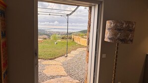 Un ingresso che dà su un giardino con un vialetto in pietra, un pergolato in metallo e vista su una città in lontananza.