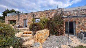 A modern stone building with a glass entrance, a small garden with rocks and shrubs, and a clear sky. - Appart heights of Ollioules in magnificent house, exceptional sea view (Ollioules)