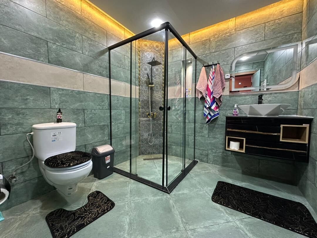 Une salle de bain moderne dotée d’une douche à parois de verre, de toilettes et d’un lavabo avec un meuble-vasque.