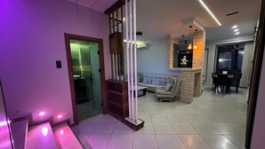 A modern living room with a sofa, a fireplace, and a dining area. - Belgaïd - T4 high standing, heated indoor pool for families only (Bir El Djir)