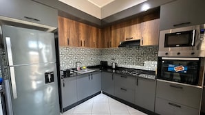 A modern kitchen with stainless steel appliances, wooden cabinets, and patterned backsplash tiles. - Belgaïd - T4 high standing, heated indoor pool for families only (Bir El Djir)