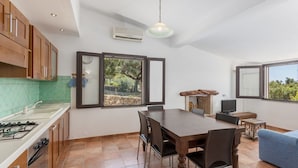 Cocina moderna con comedor, ventanas amplias y televisor.
