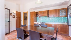 Una cocina moderna con armarios de madera, un comedor amplio y un salpicadero de azulejos.