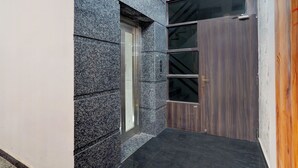 Une entrée moderne, avec une façade en granit, une porte en bois et une fenêtre en verre.