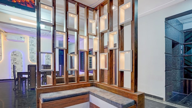 Un intérieur moderne avec un banc en bois, un mur orné de plusieurs miroirs encadrés et un sol carrelé foncé.