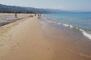 Ein Strand mit Menschen, die spazieren gehen und sitzen.