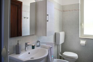Ein Badezimmer mit Waschbecken, Spiegel, Schrank, Toilette und Fenster.