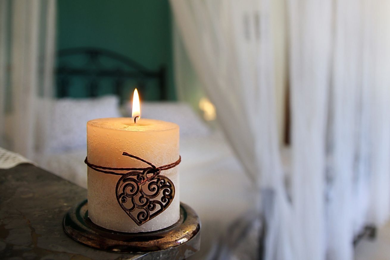 A lit candle with a heart-shaped tag on a metal stand.