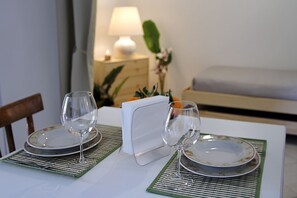 Ein Esstisch mit zwei Tellern, zwei Weingläsern, einem weißen Serviettenhalter und einer Lampe im Hintergrund.
