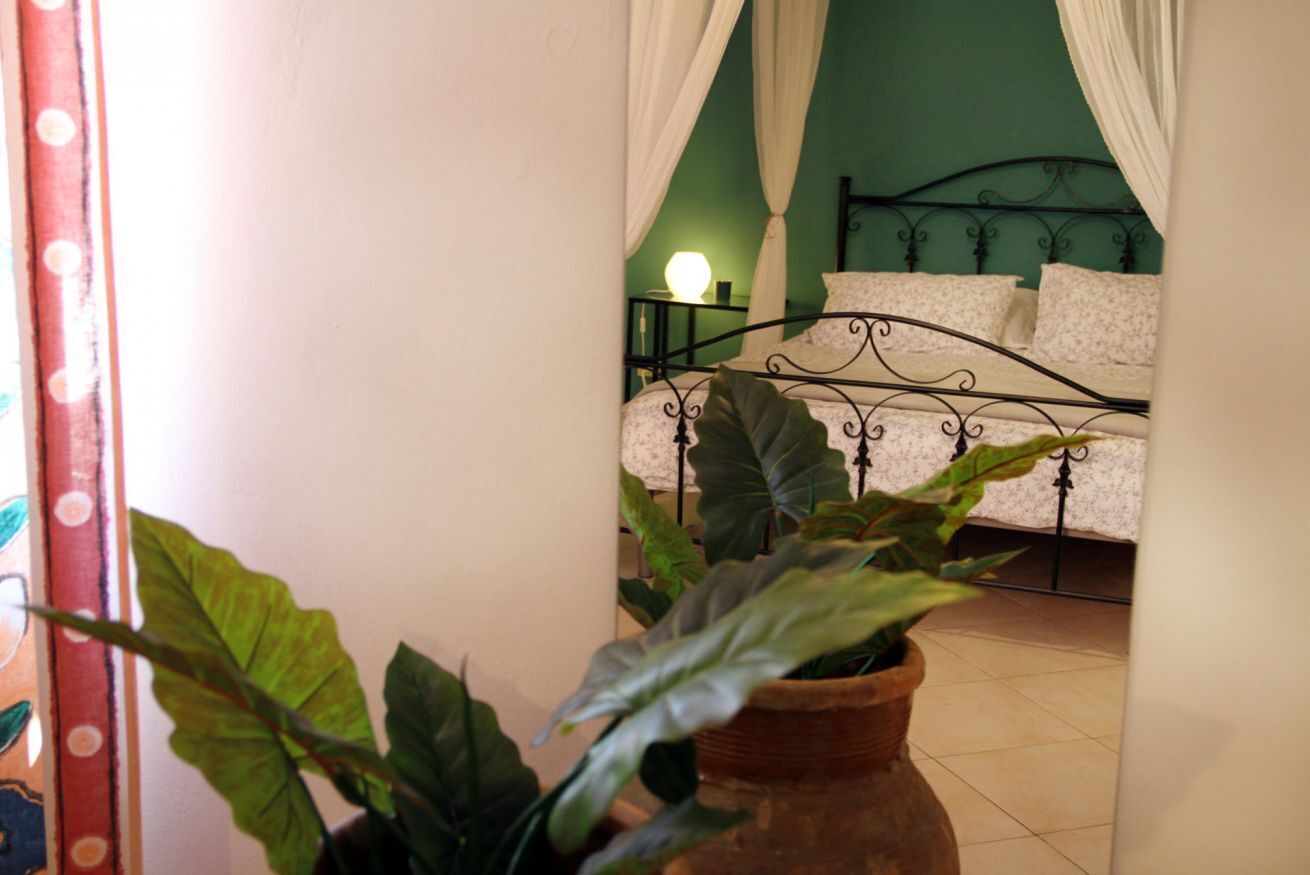 A bedroom with a bed, a nightstand, and a potted plant.