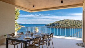 An outdoor dining area with a table set for four, overlooking a scenic coastal view. - Villa Cristal Blue by Villas Guide (Blato)
