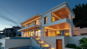 A modern two-story house with a balcony, a staircase, and a pool area. - Villa Cristal Blue by Villas Guide (Blato)
