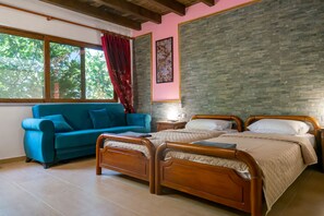 A bedroom with a wooden bed, a blue sofa, a nightstand, and a window with curtains. - Koksinou Apartment 2 (96W9+4H Koskinou, Greece)
