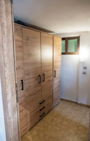 A room with a wooden wardrobe, a small window, and a tiled floor. - Koksinou Apartment 2 (96W9+4H Koskinou, Greece)