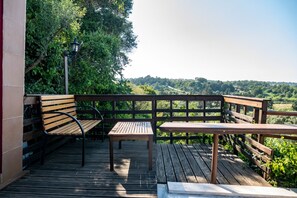 Eine Holzterrasse mit einer Bank, einem Tisch und einer Lampe.