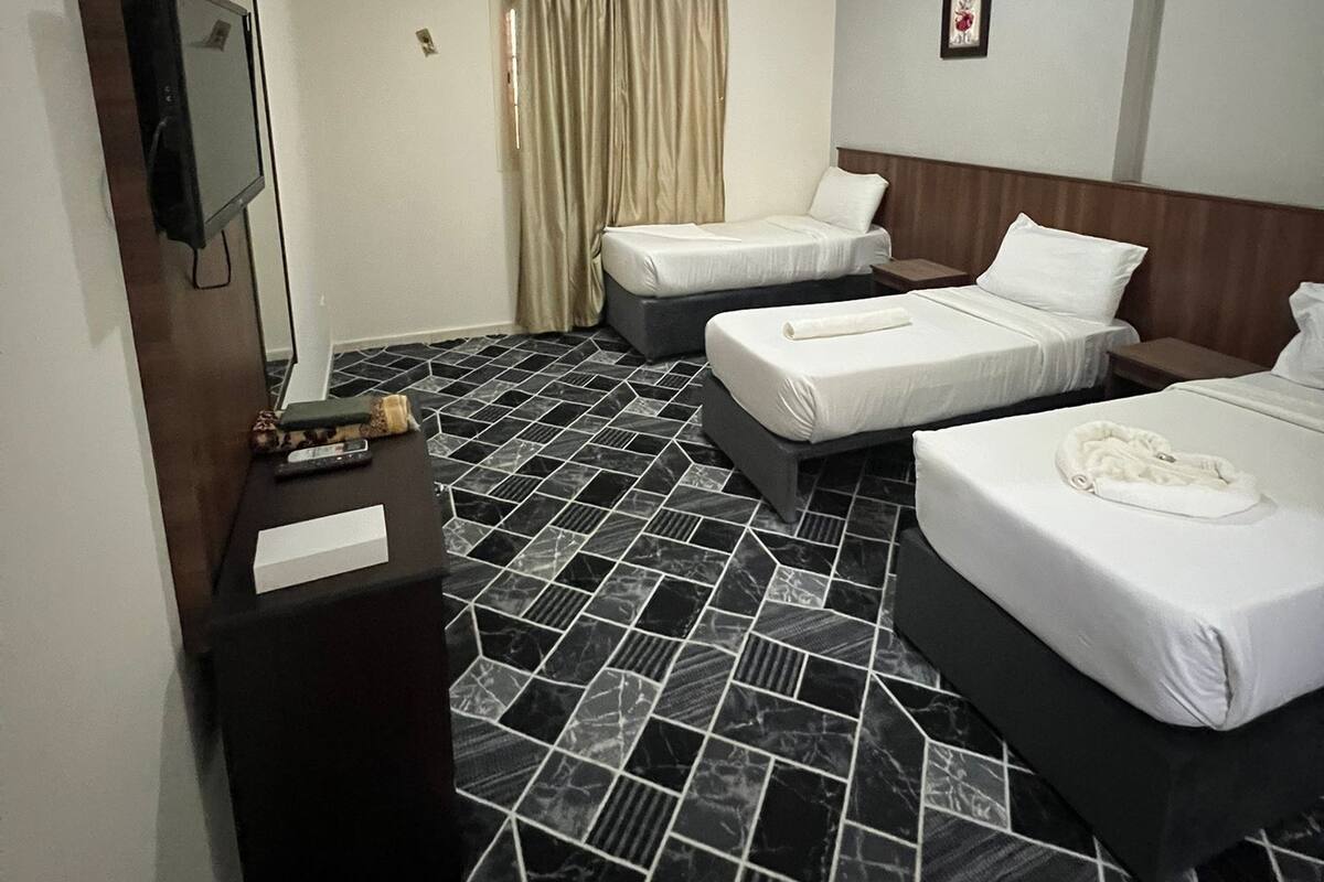 Una habitación de hotel con dos camas, un escritorio, un espejo y una ventana con cortinas.