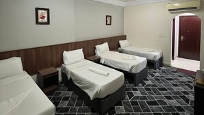 Ein Hotelzimmer mit vier Betten, einem Fliesenboden und einer Tür zum Außenbereich.