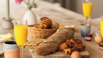 Ein Frühstückstisch mit Brot, Gebäck, Eiern und Orangensaft.