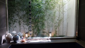 A room with a large window, bamboo plants, and traditional vases.