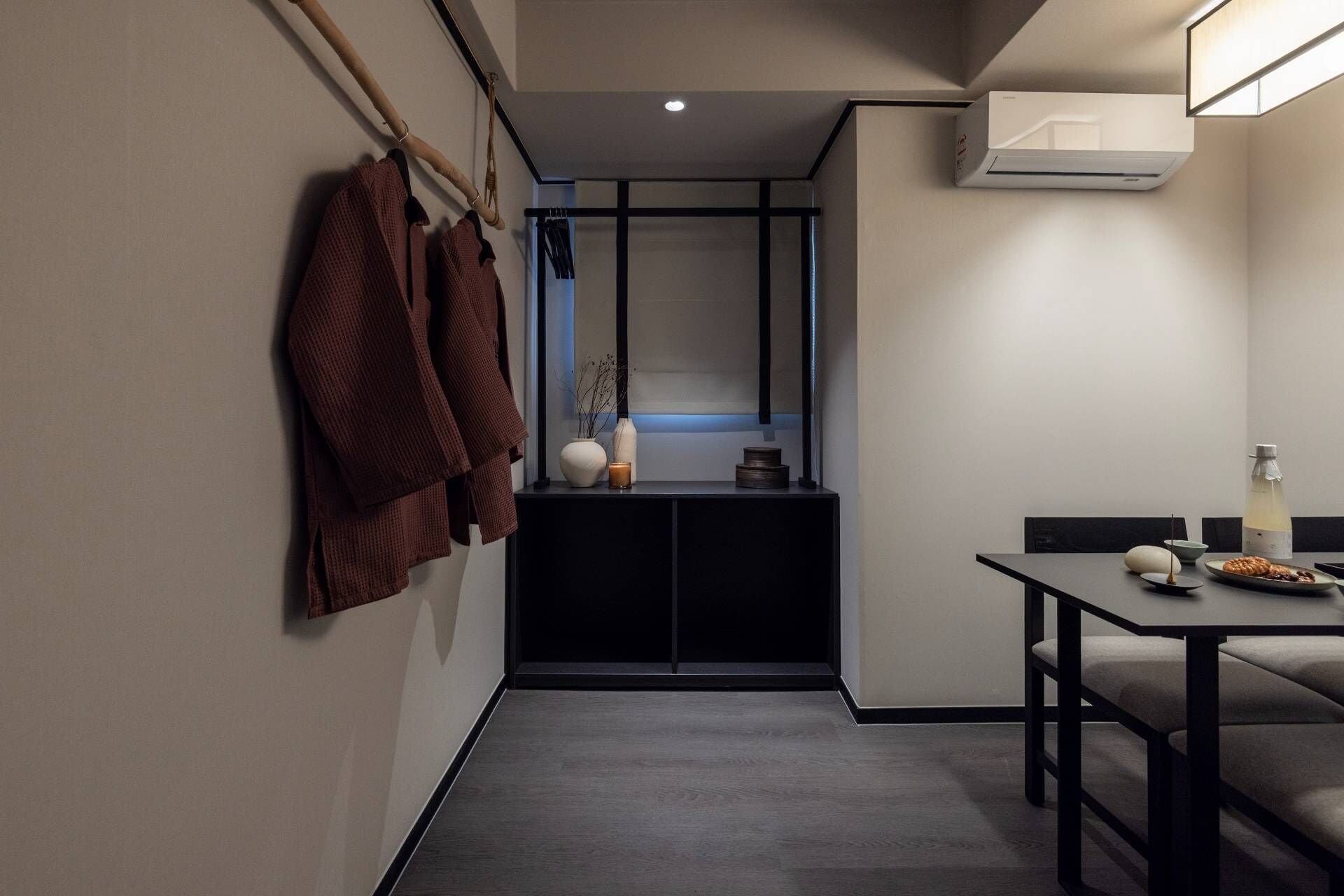 Un bagno moderno con un porta asciugamani, uno specchio, un lavandino e un tavolo con una bottiglia e un piatto.