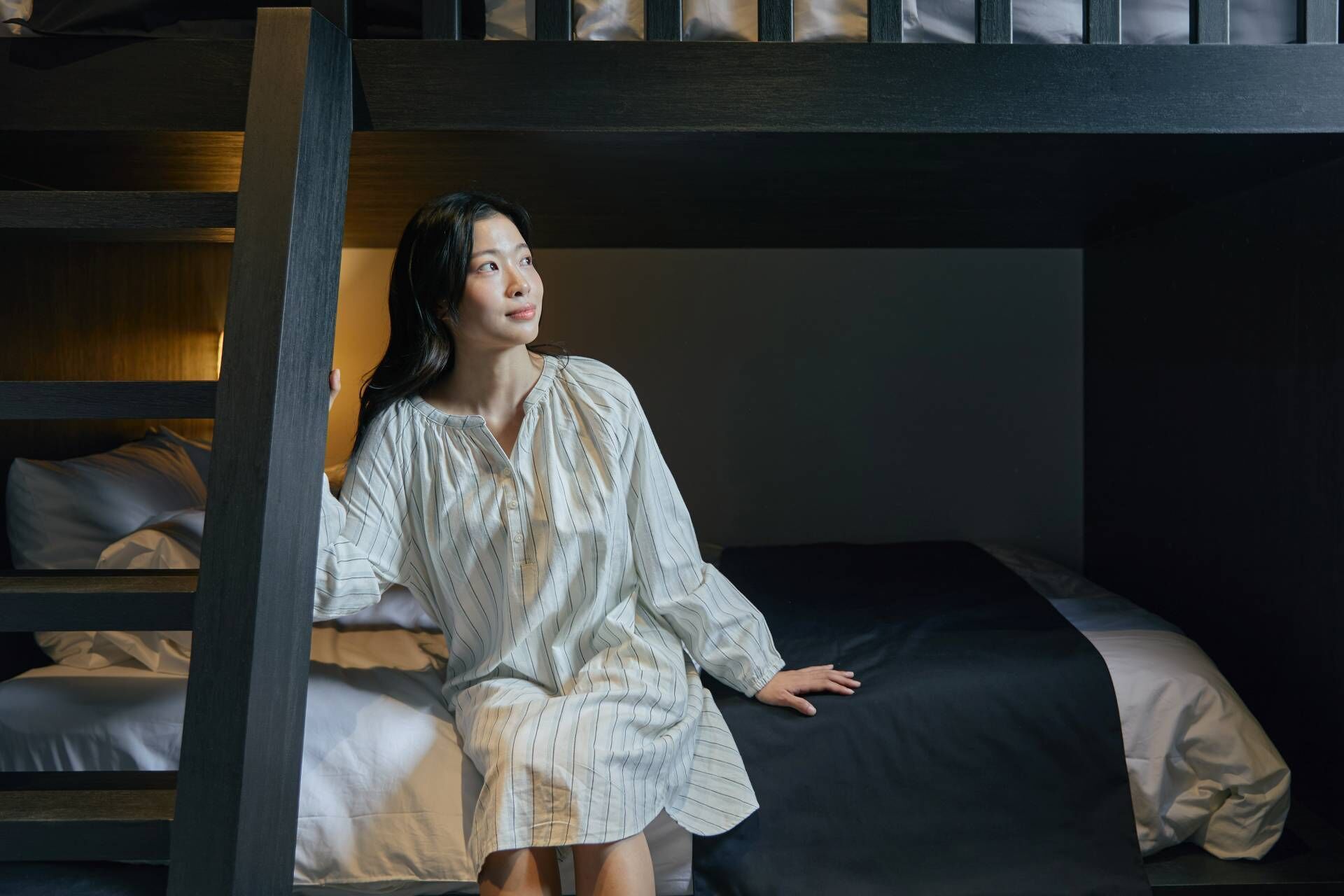 A bunk bed with a person sitting on the lower bunk.